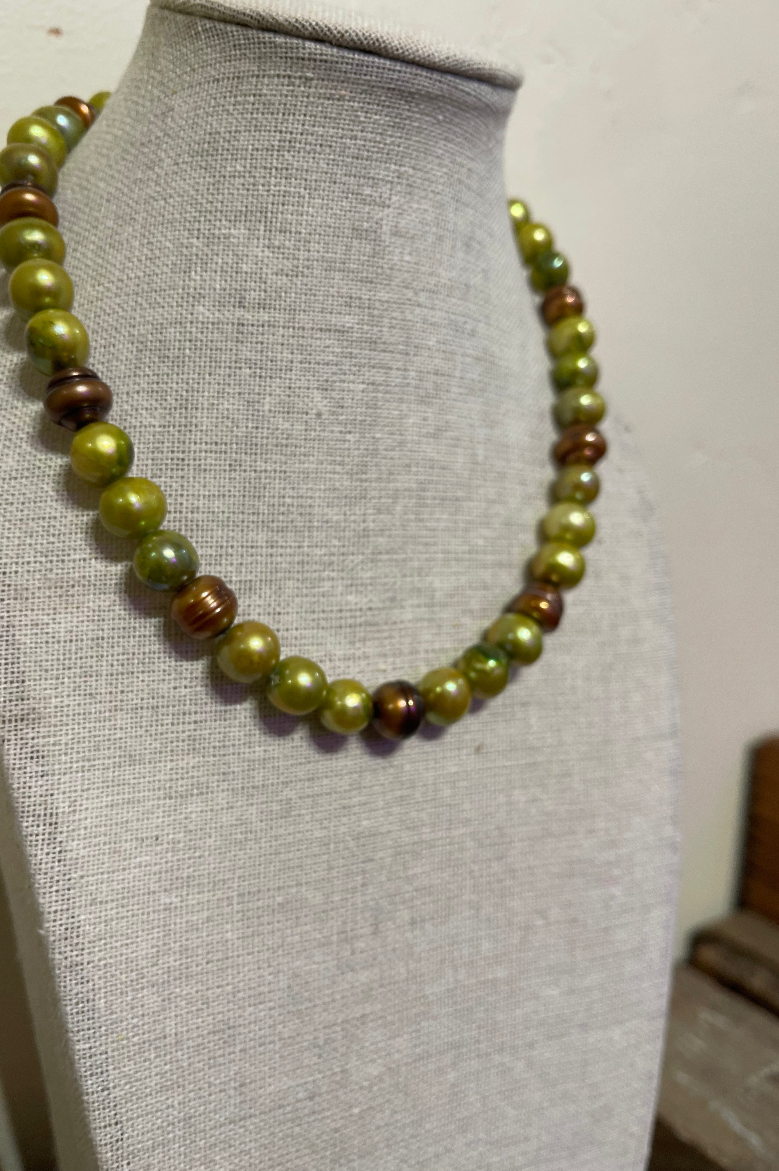 Necklace with green and brown 10mm freshwater pearls on a mannequin bust.
