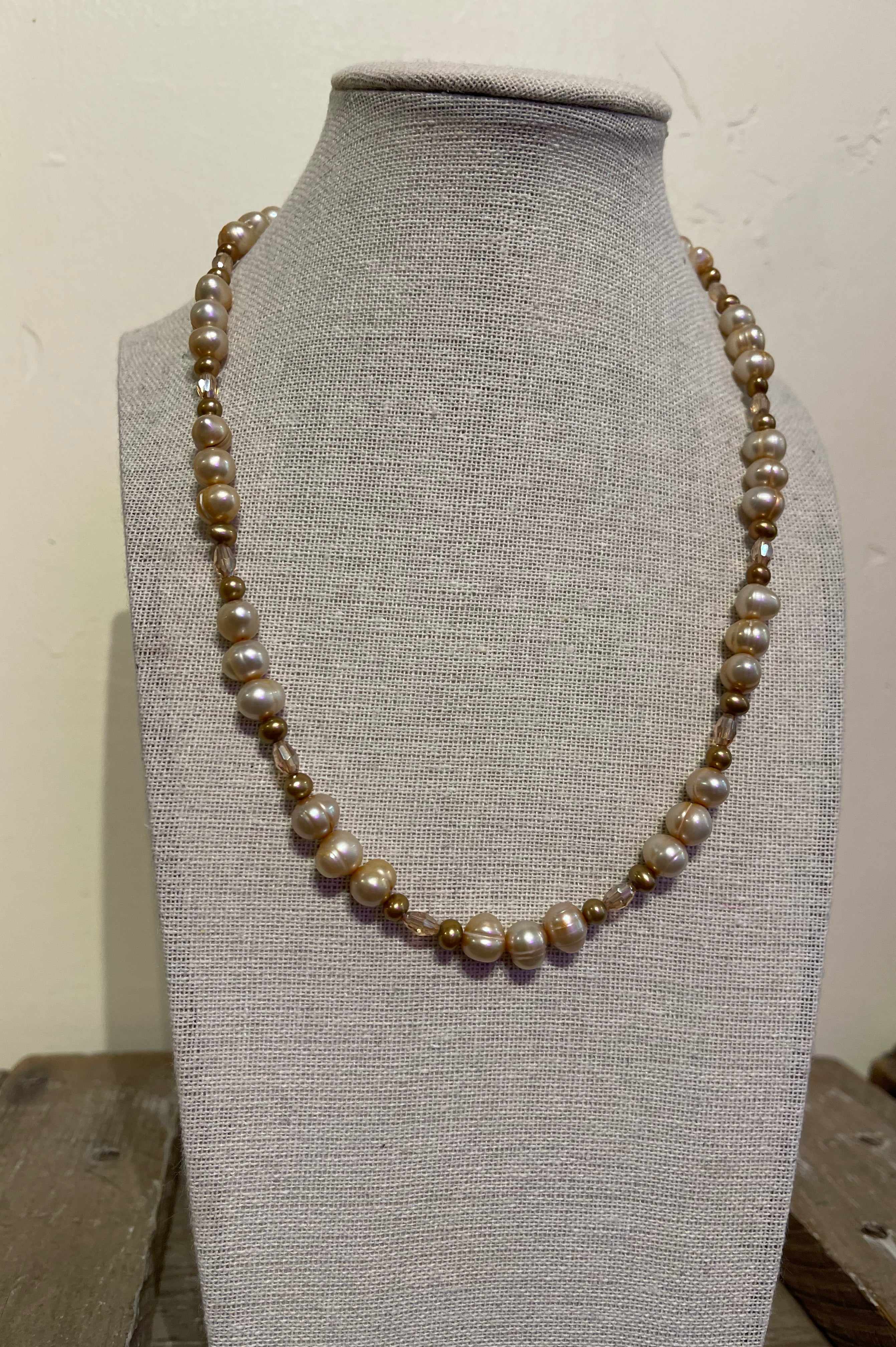 Pearl necklace on a gray mannequin bust against a white background