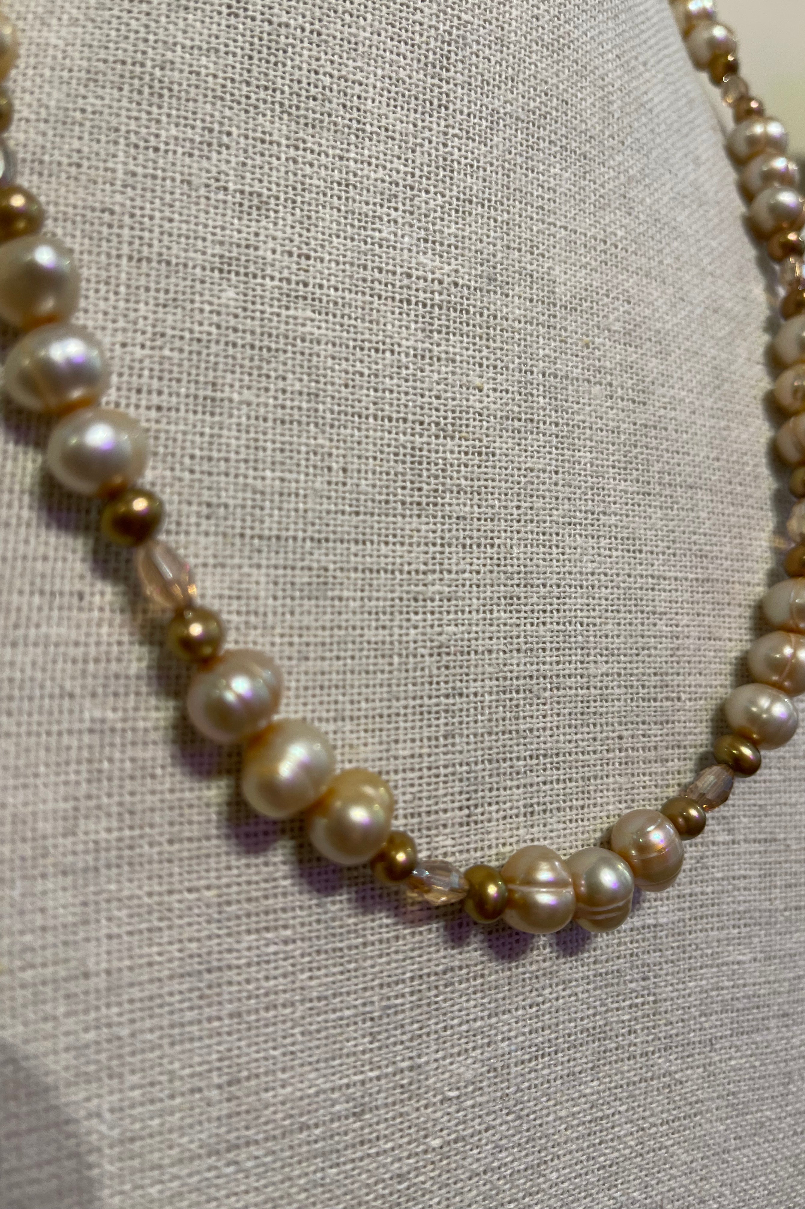 Necklace with pearls and gold beads on a textured fabric background