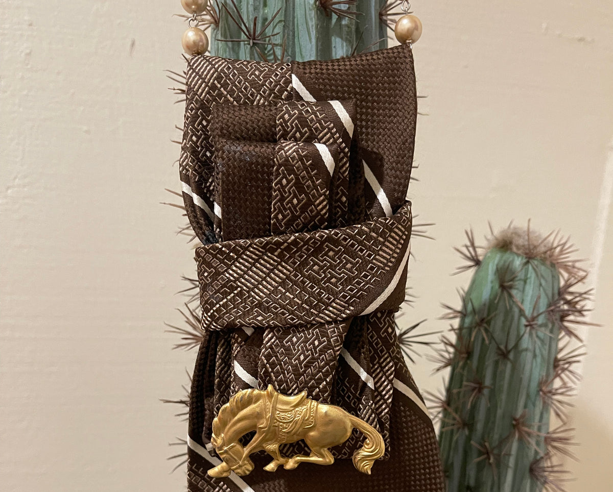 Handcrafted vintage tie necklace by Copper & Lace Western Boutique featuring an authentic 1970s brown patterned necktie, champagne pearl strand, and vintage gold-tone horse brooch.