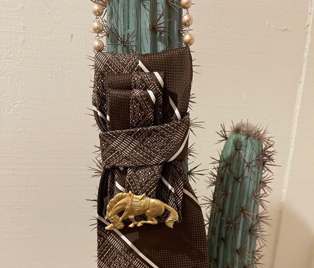 Handcrafted vintage tie necklace by Copper & Lace Western Boutique featuring an authentic 1970s brown patterned necktie, champagne pearl strand, and vintage gold-tone horse brooch.