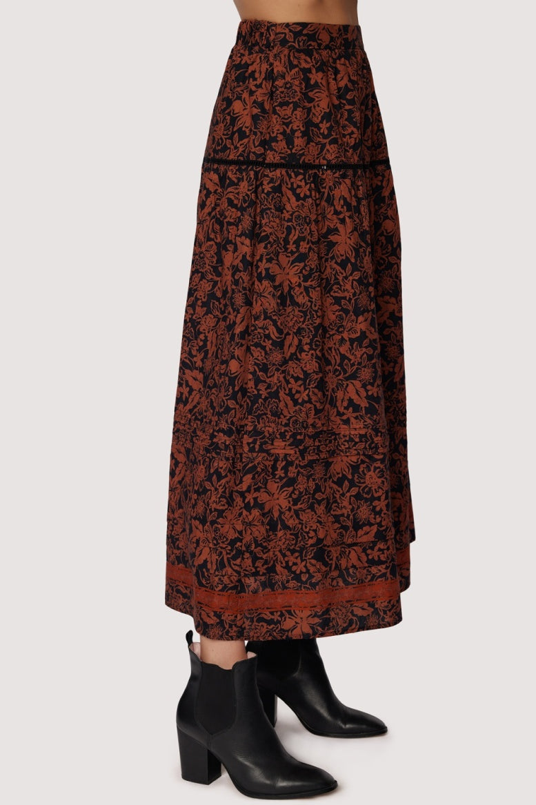 Long patterned skirt worn with black boots on a white background