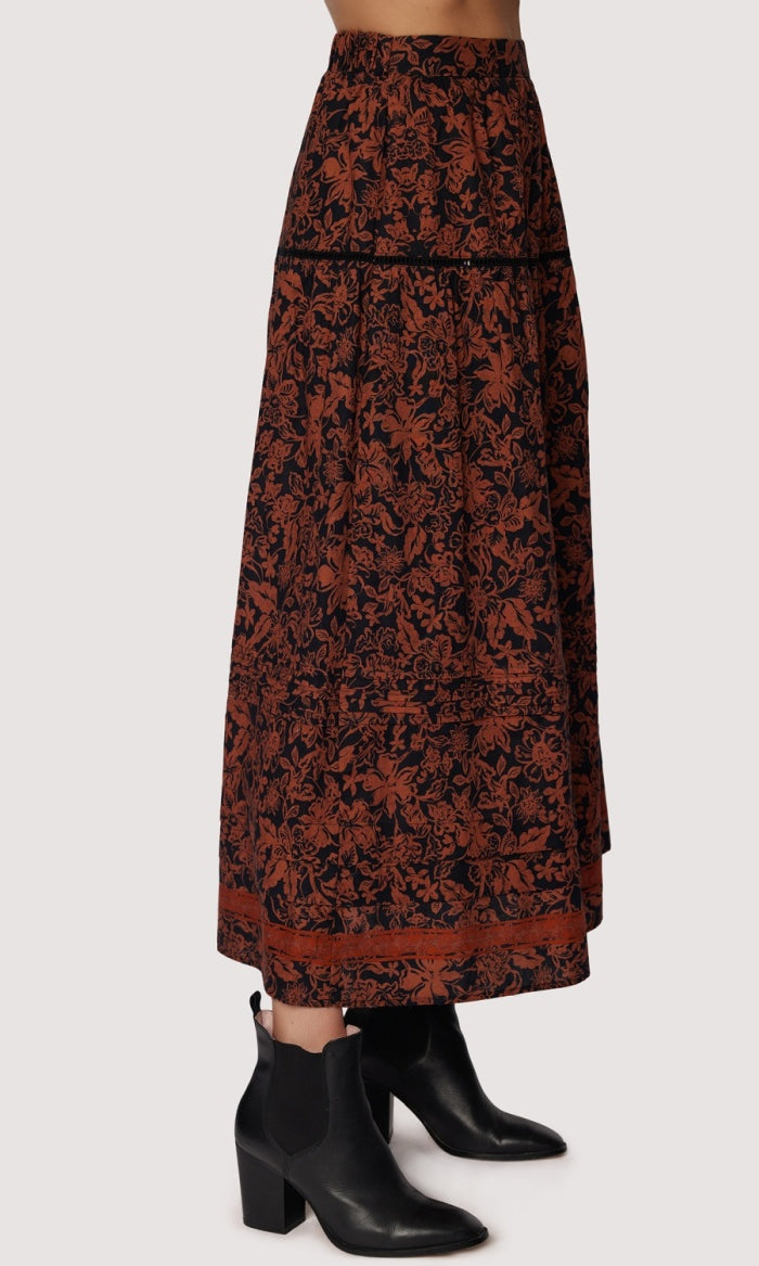 Long patterned skirt worn with black boots on a white background