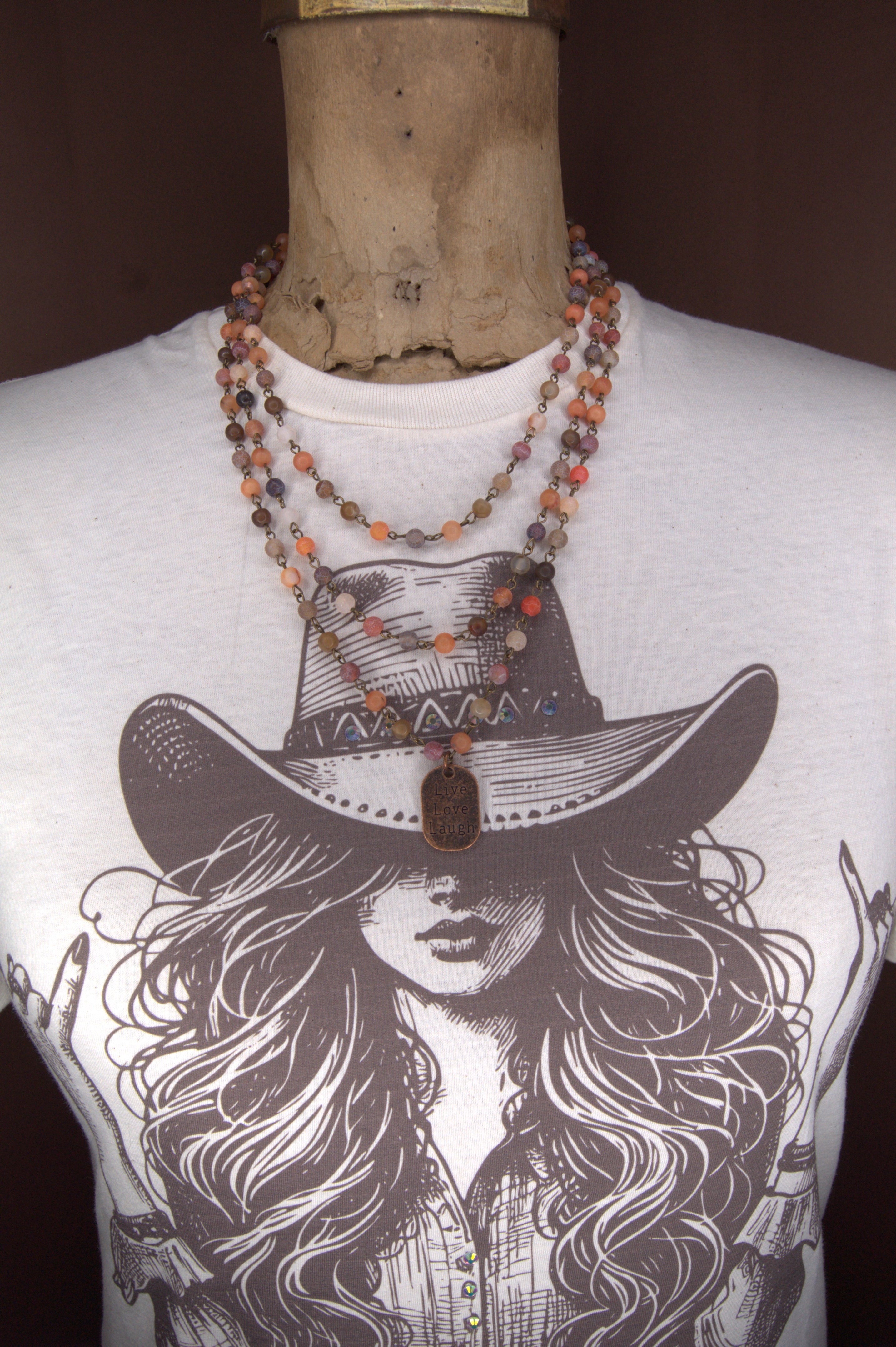 Mannequin torso with a 2 strand 6mm beaded necklace in 6mm Red Moss, Orange-Red Moss, and Brown Line Matte Agate beads with a copper tag stamped with Live Love Laugh
