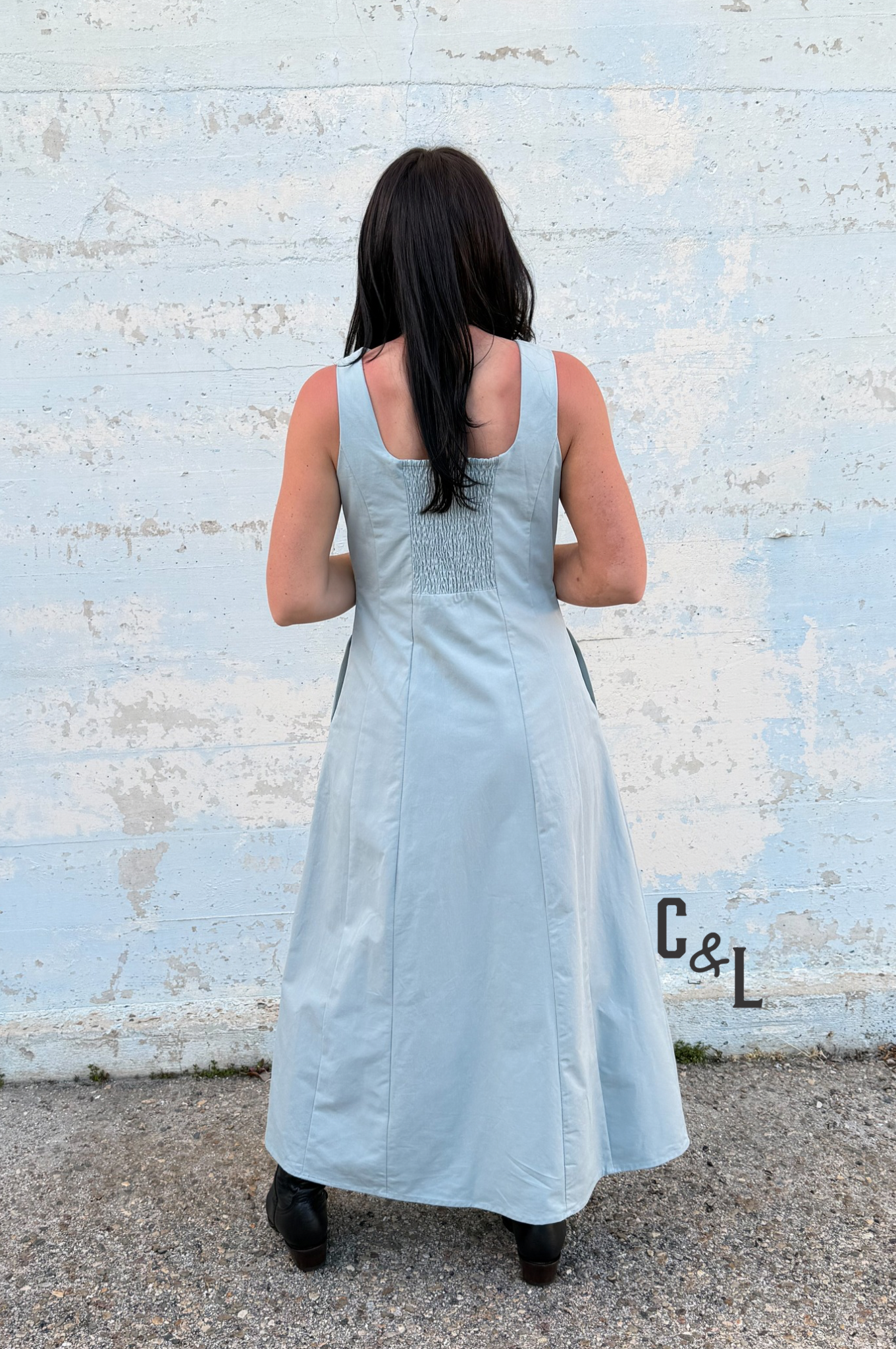 Woman wearing a light blue dress standing against a textured white wall.