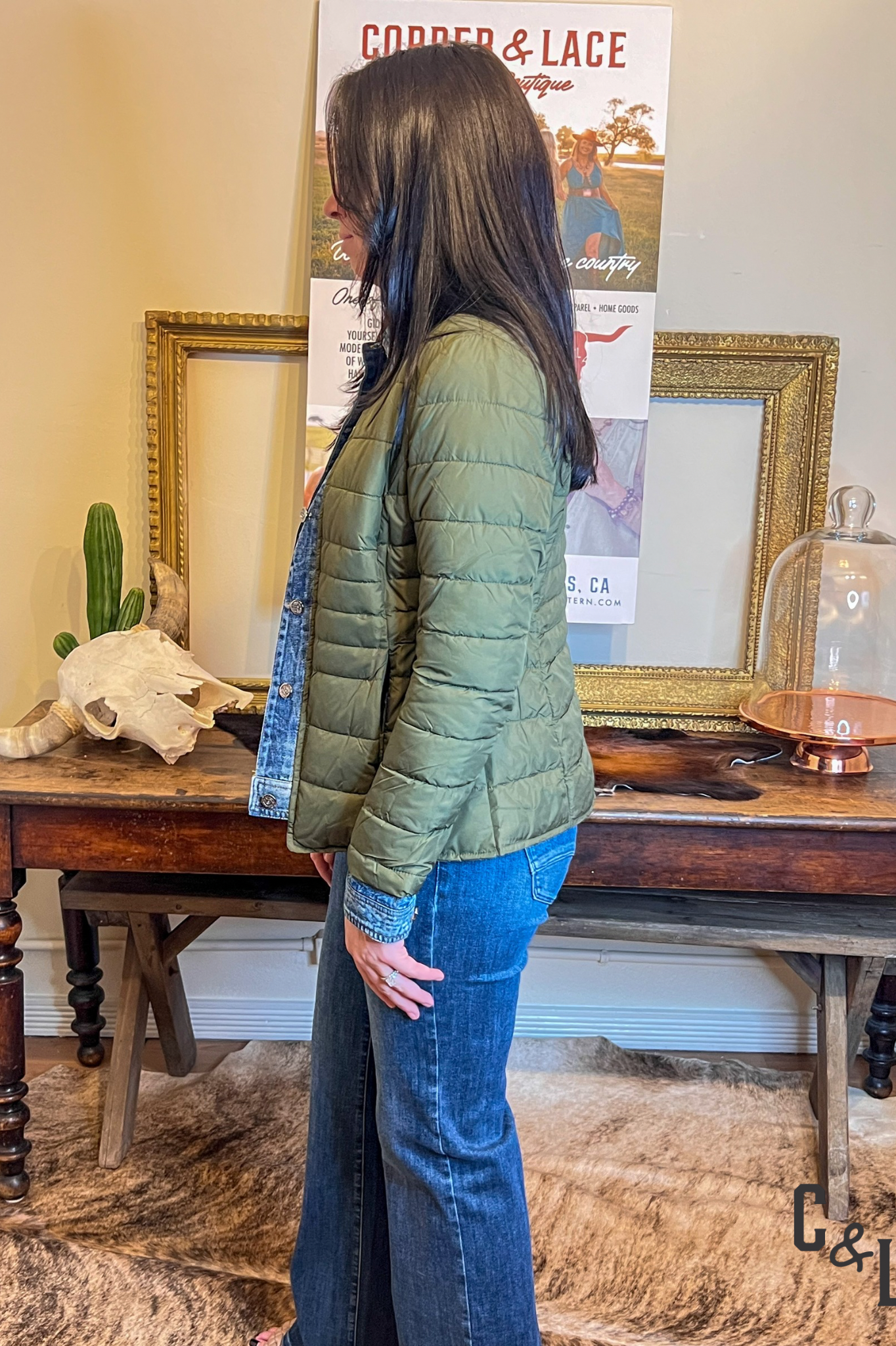 Person wearing a green puffer jacket standing in front of a table with decorative items.