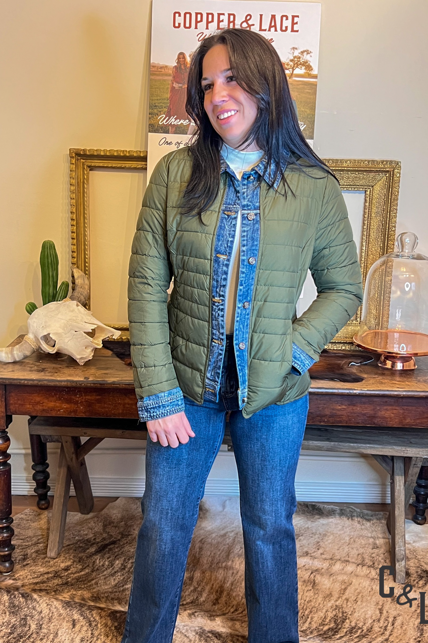 Woman wearing a green quilted jacket with denim blue trim on cuffs and front button area and collar