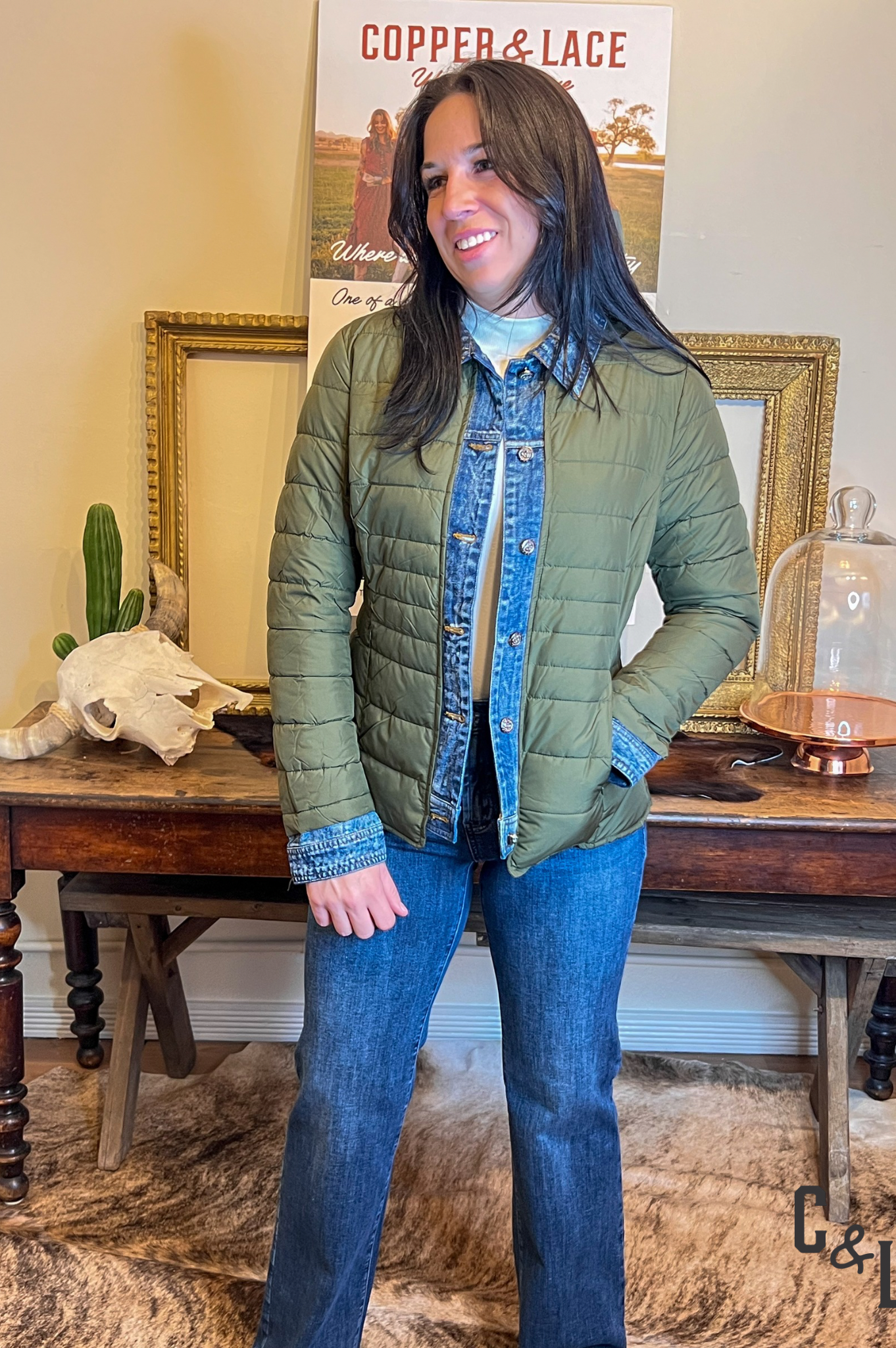 Woman wearing a green quilted jacket with denim blue trim on cuffs and front button area and collar