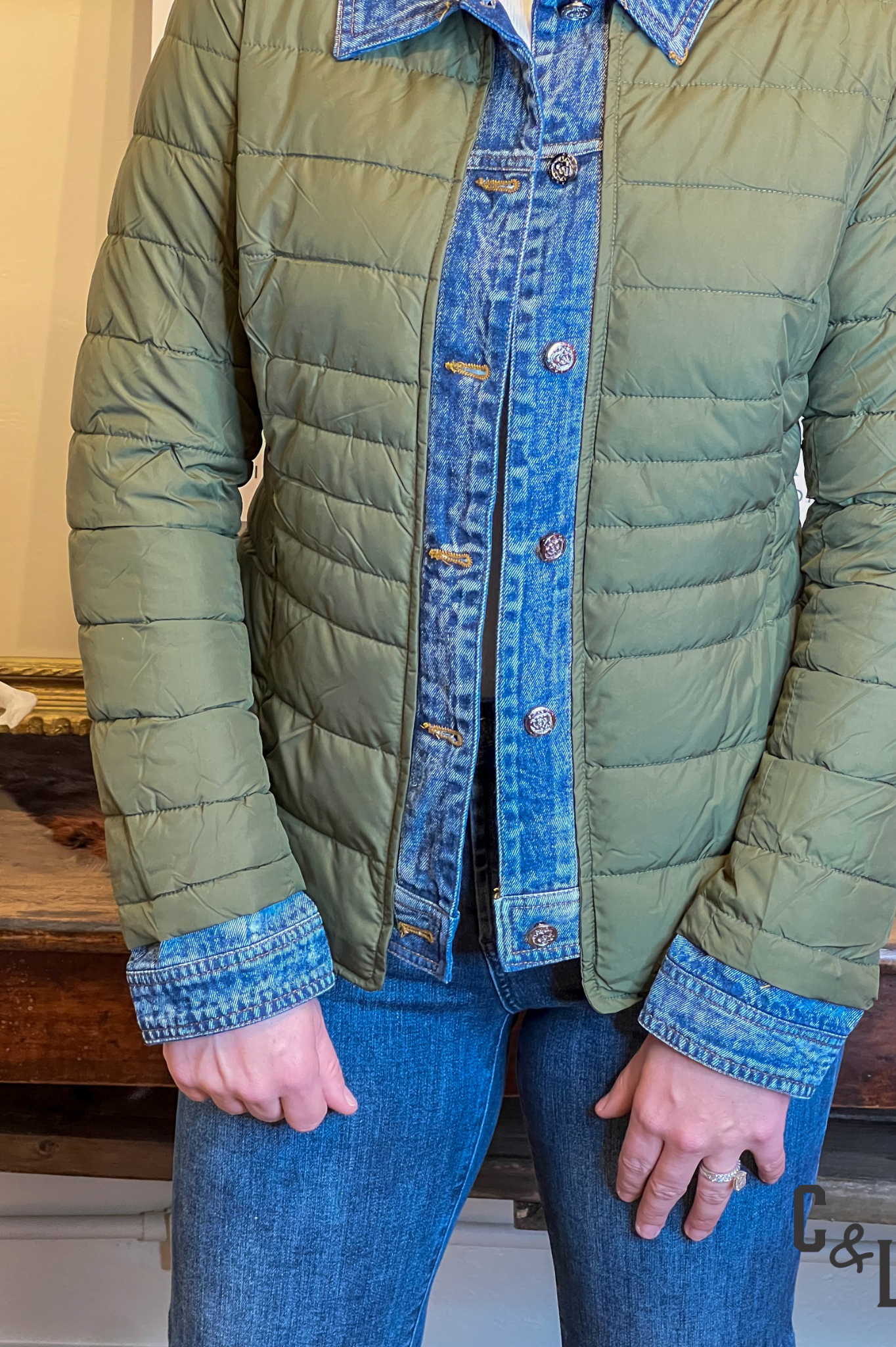 Green quilted jacket with denim collar and cuffs worn by a person indoors.