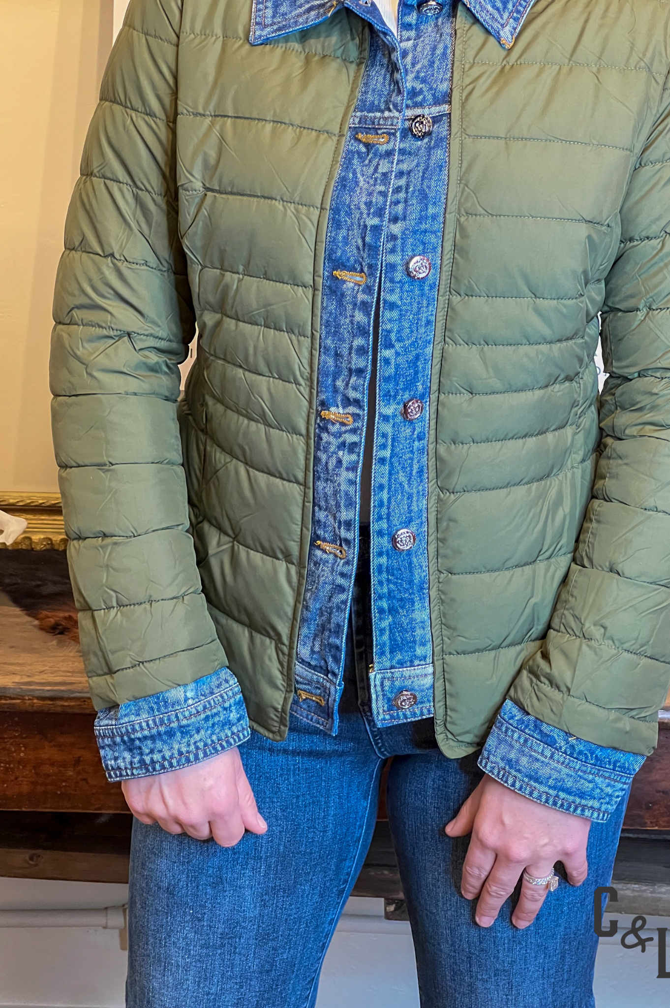 Green quilted jacket with denim collar and cuffs worn by a person indoors.