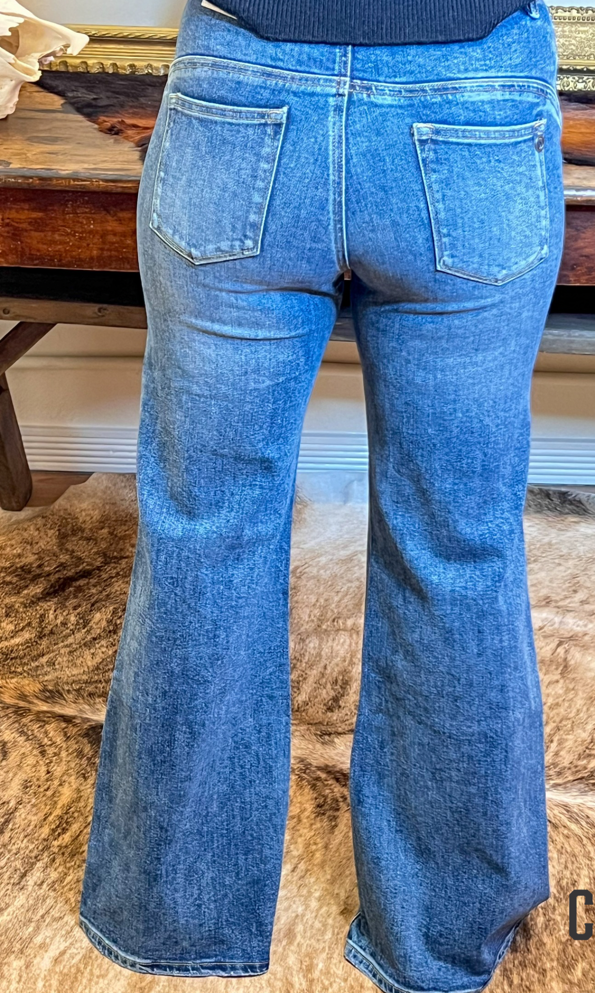 Blue flared jeans on a wooden surface with a blurred background