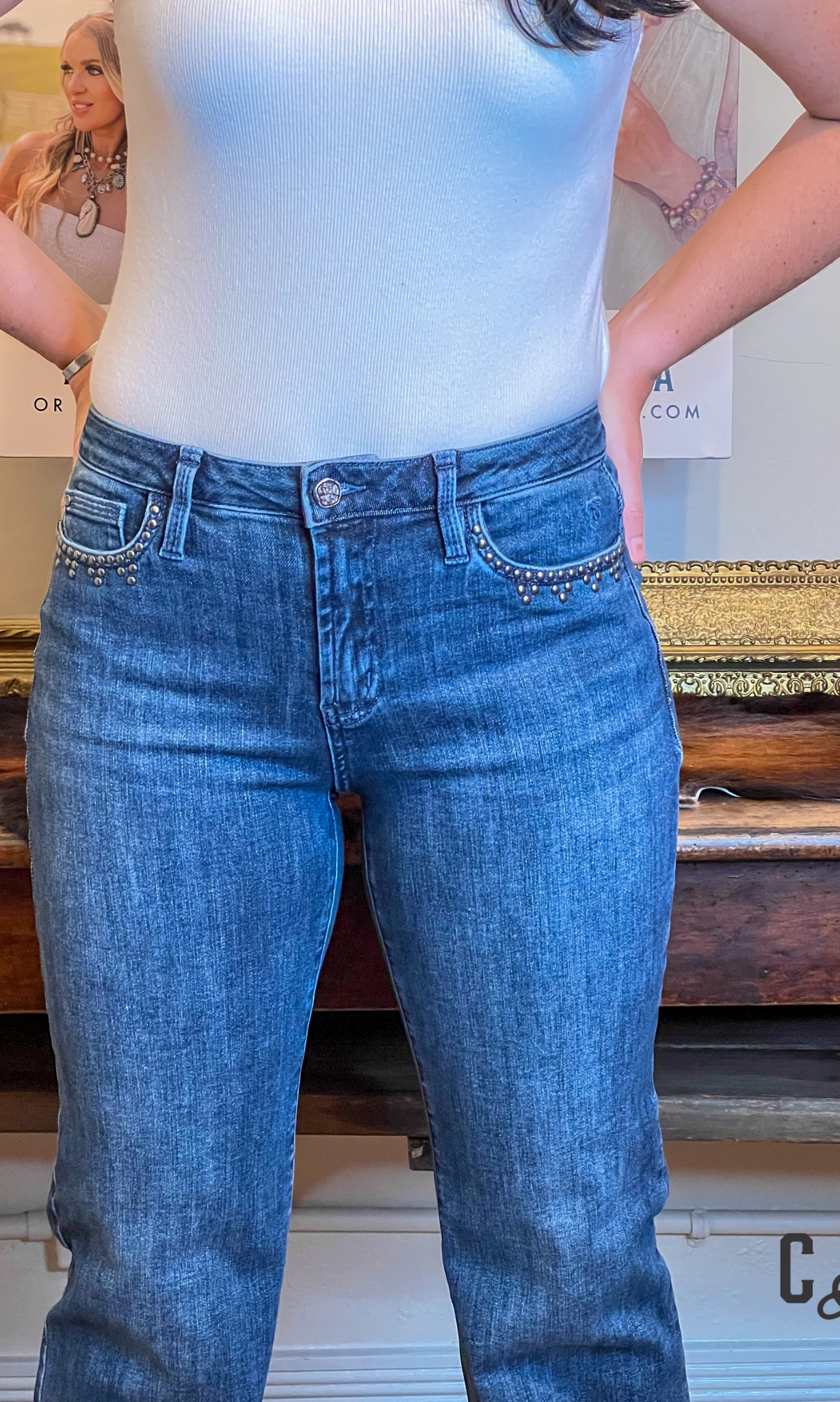 Person wearing blue jeans and a light blue top in an indoor setting with a blurred background