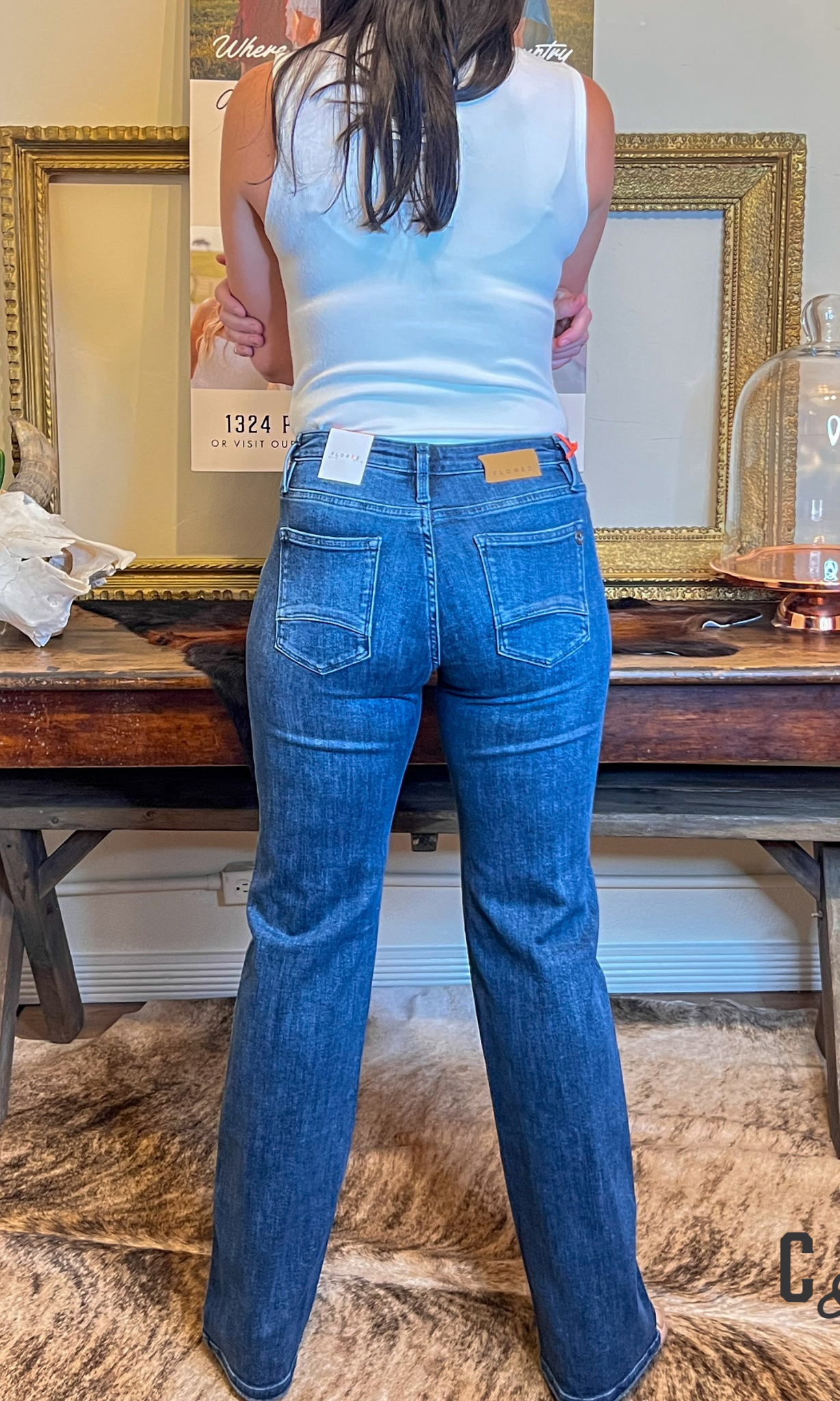 Person wearing blue jeans and a light blue top standing in a room with decorative elements.