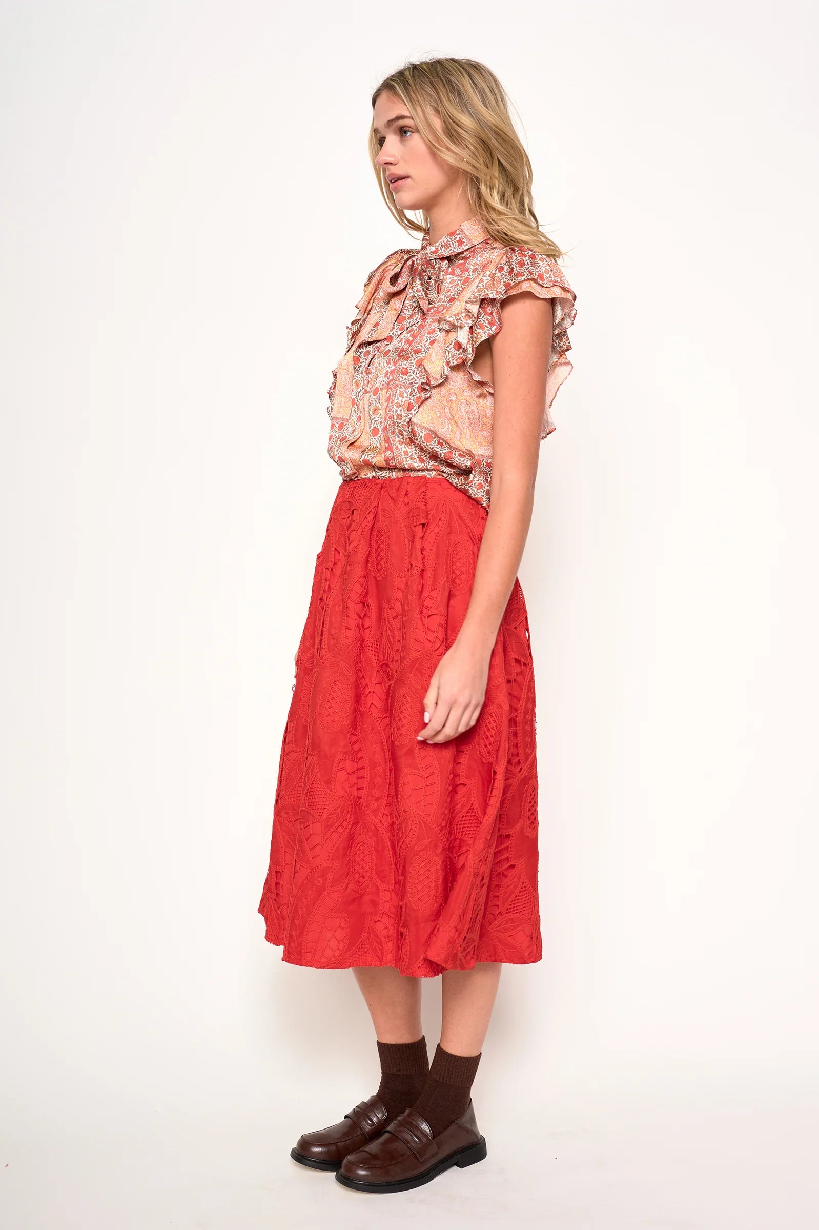 Woman wearing a floral blouse in orange, rust and ivory satin