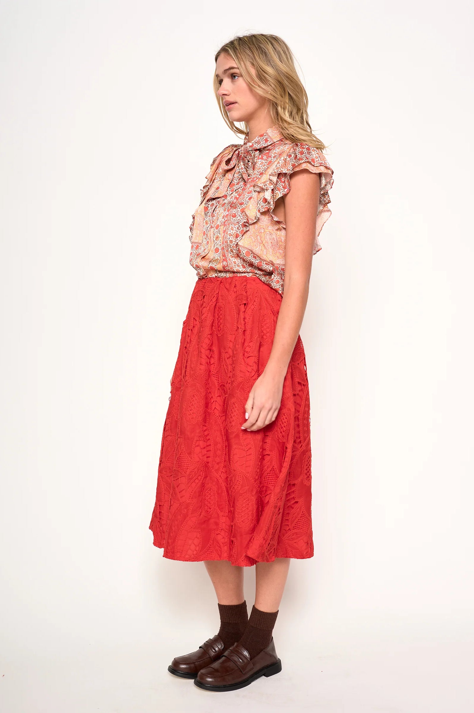 Woman wearing a floral blouse in orange, rust and ivory satin