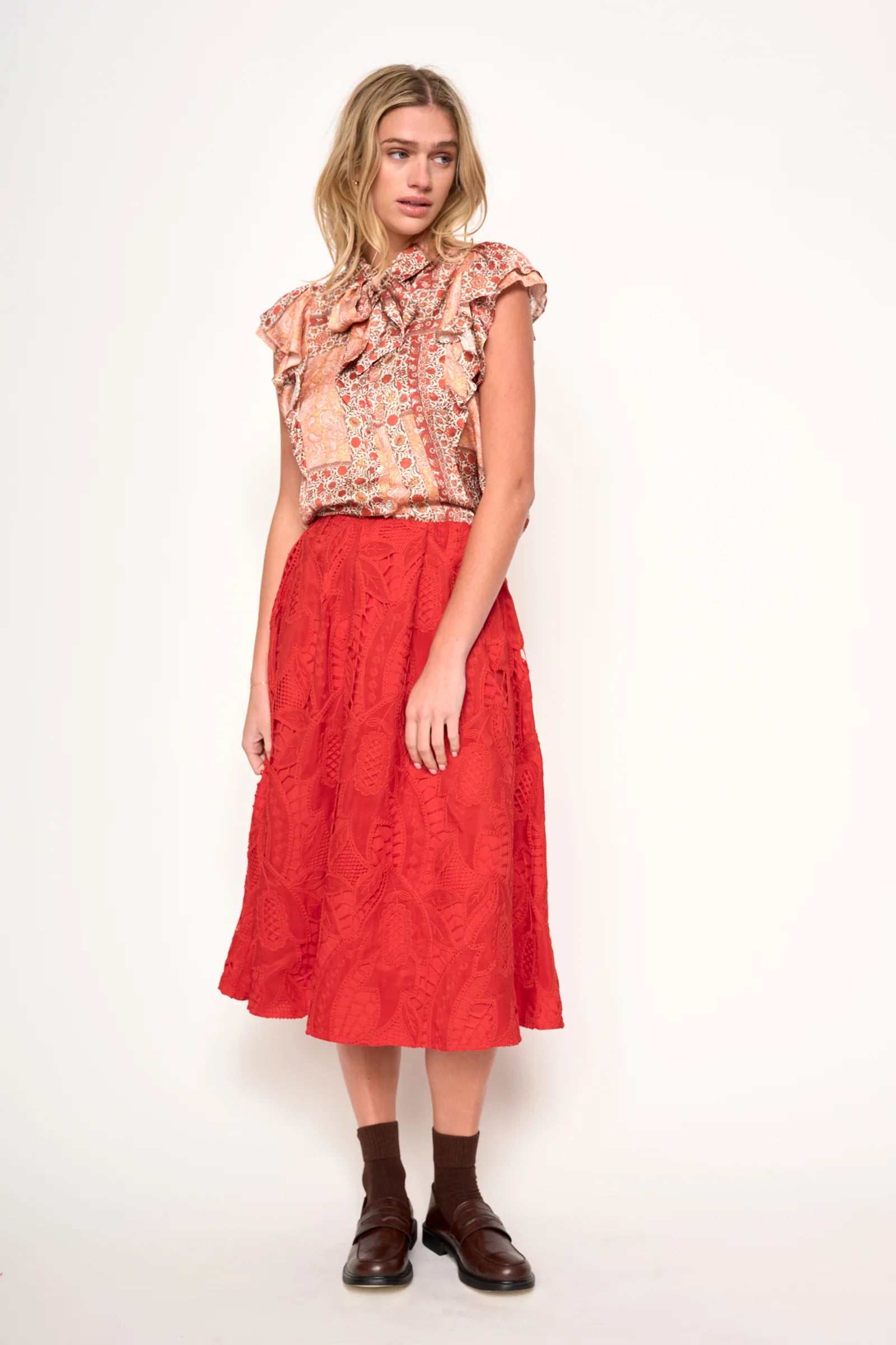 Woman wearing a floral blouse in orange, rust and ivory satin