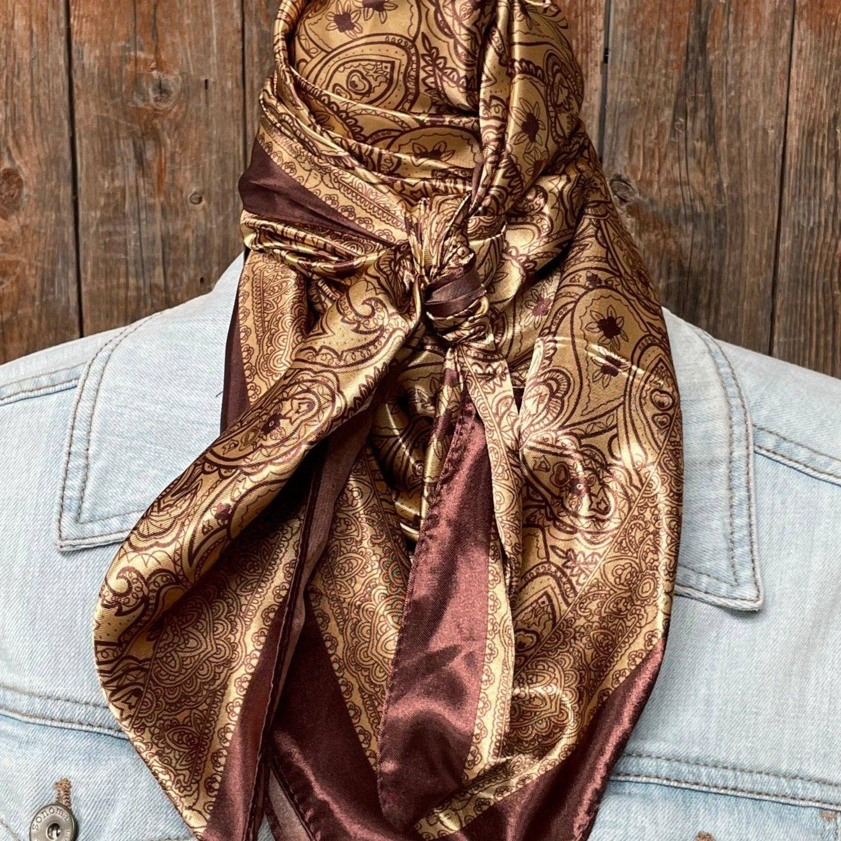 Brown paisley scarf draped over a light blue denim jacket against a wooden background