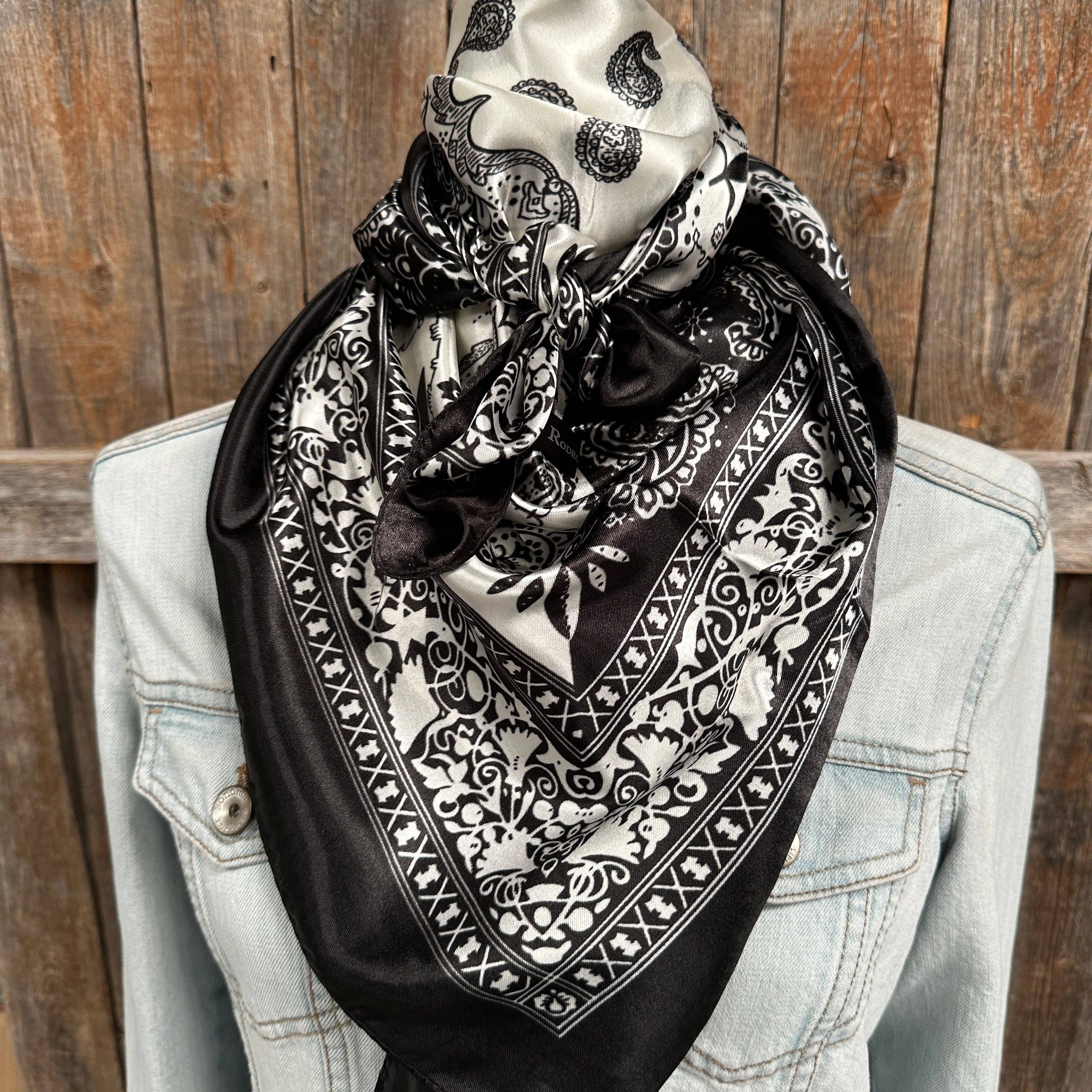Black and white patterned scarf draped over a light blue denim jacket against a wooden background