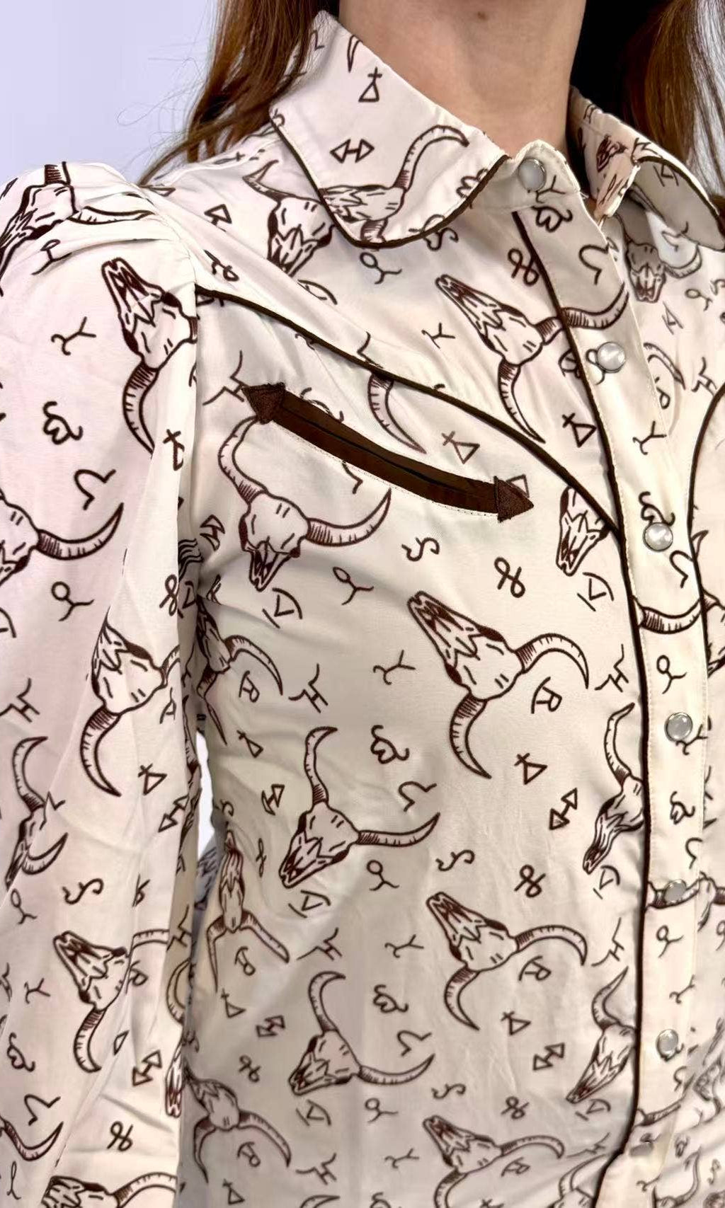 Person wearing a patterned shirt with longhorn bull design on a light background