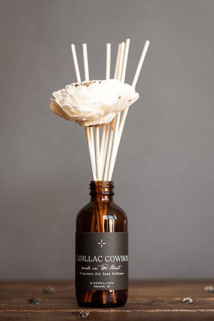 Diffuser with reeds and decorative flower on a wooden surface with a gray background