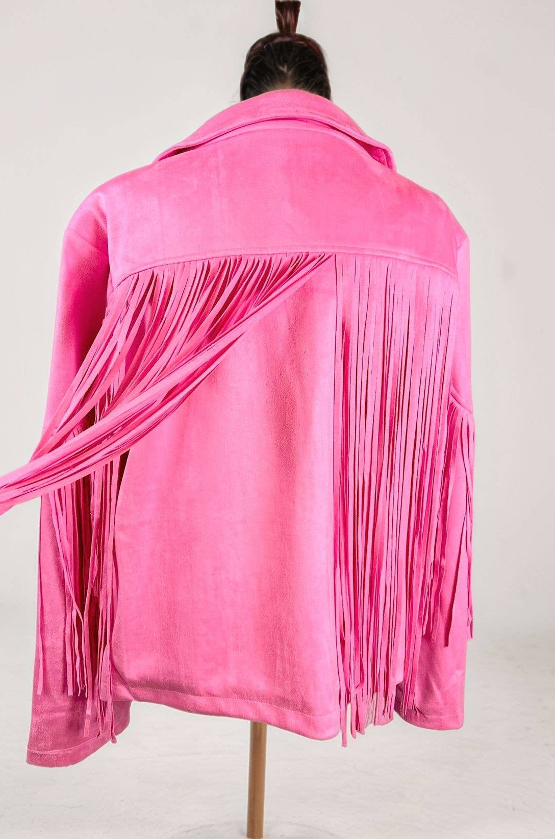Pink fringed jacket on a mannequin against a white background