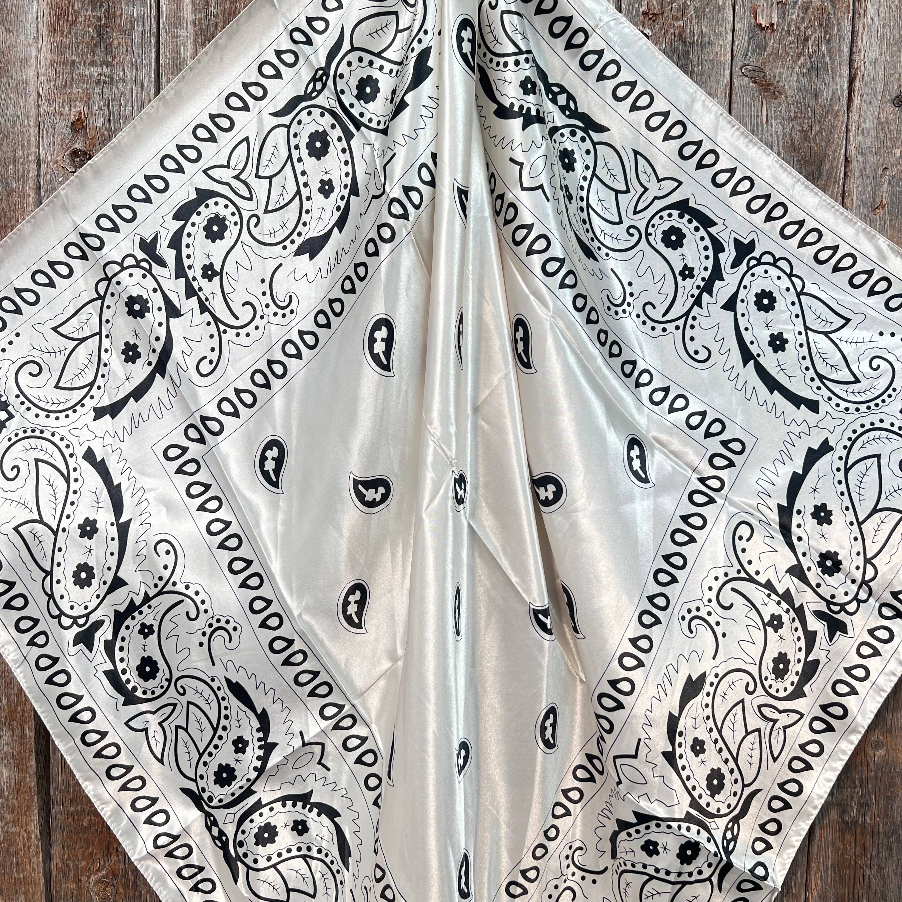 Black paisley pattern on a white fabric draped over a wooden surface