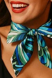 Woman wearing a blue and green patterned scarf around her neck against a blurred background