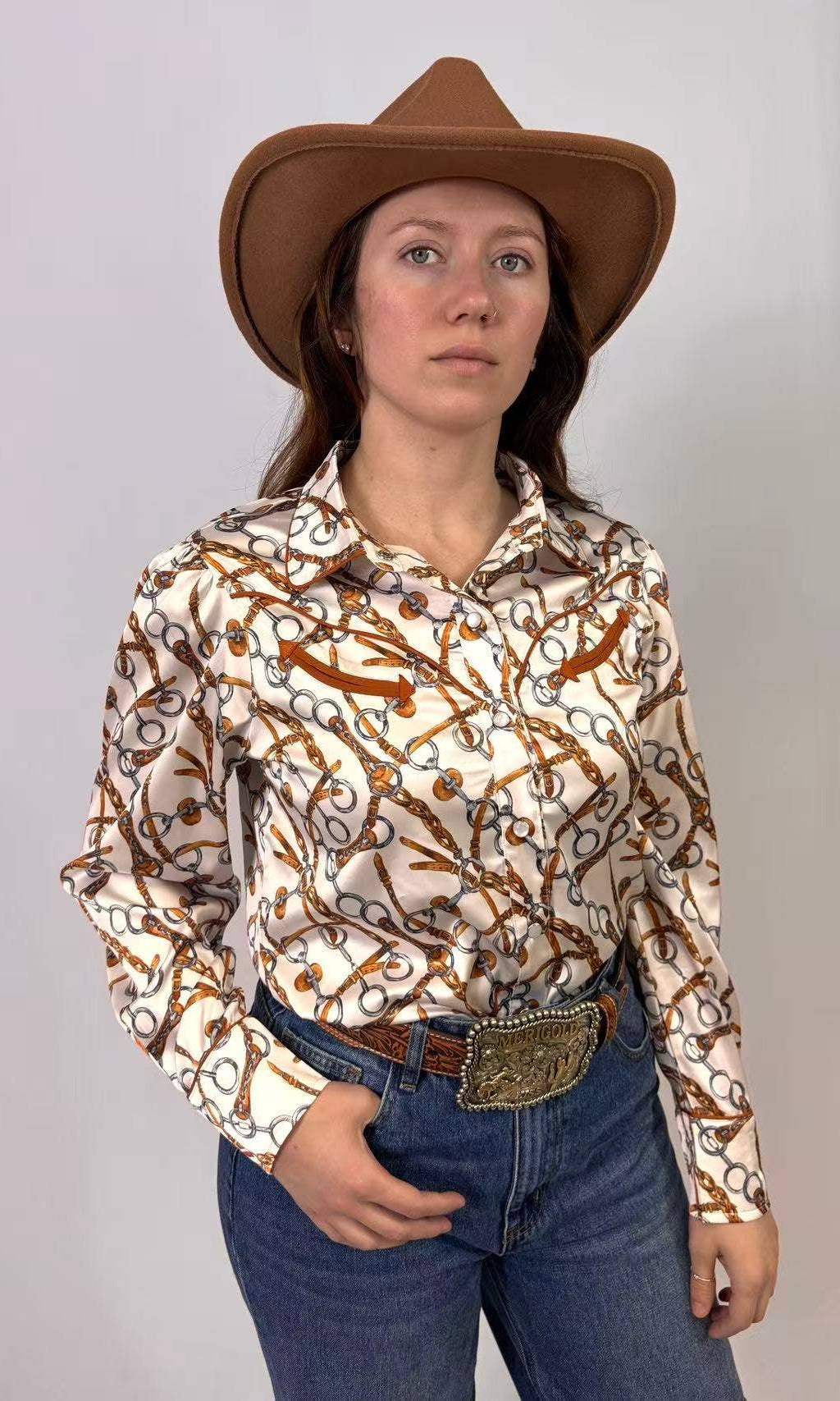 Person wearing a patterned shirt, jeans, and a cowboy hat against a plain background