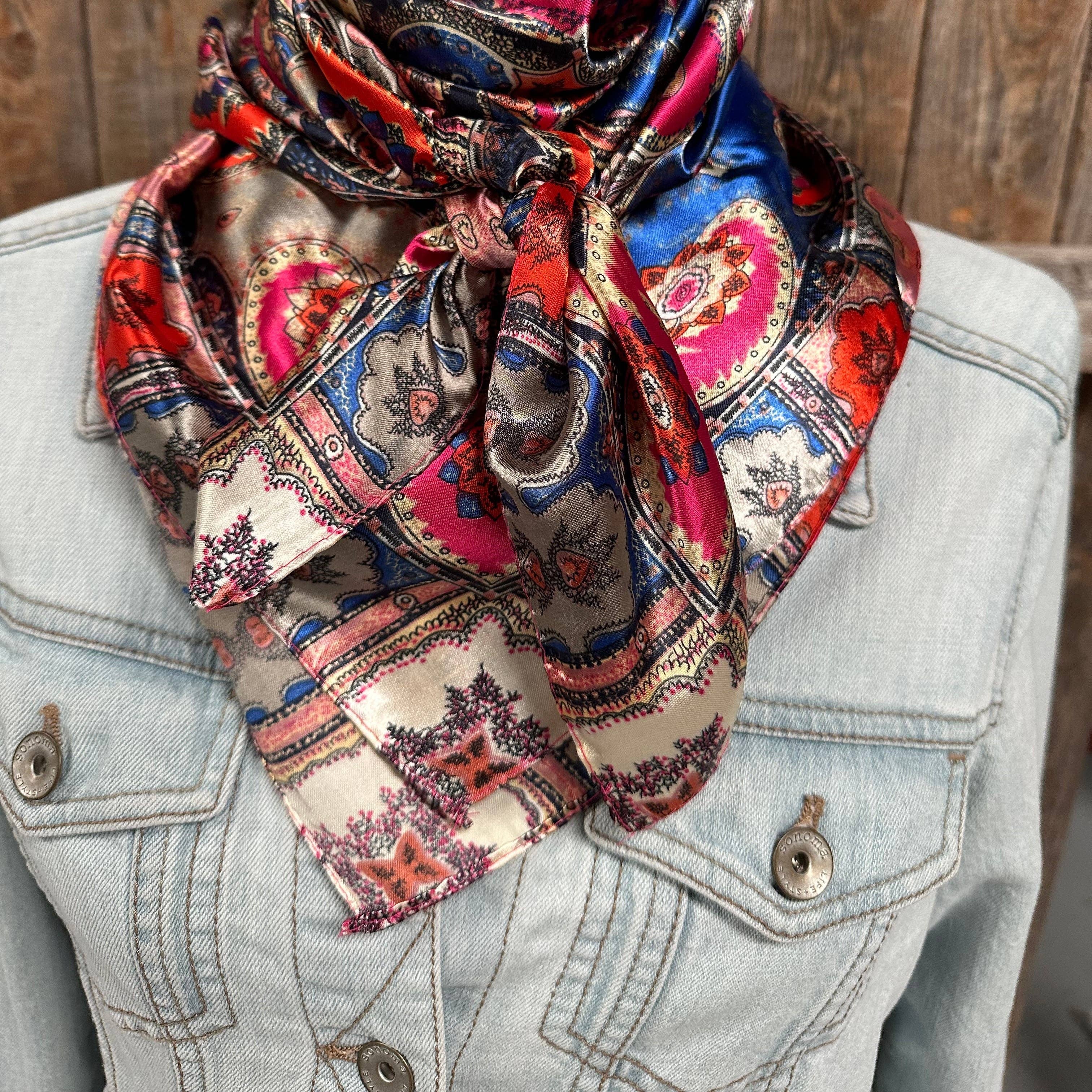 Colorful patterned scarf draped over a denim jacket against a wooden background