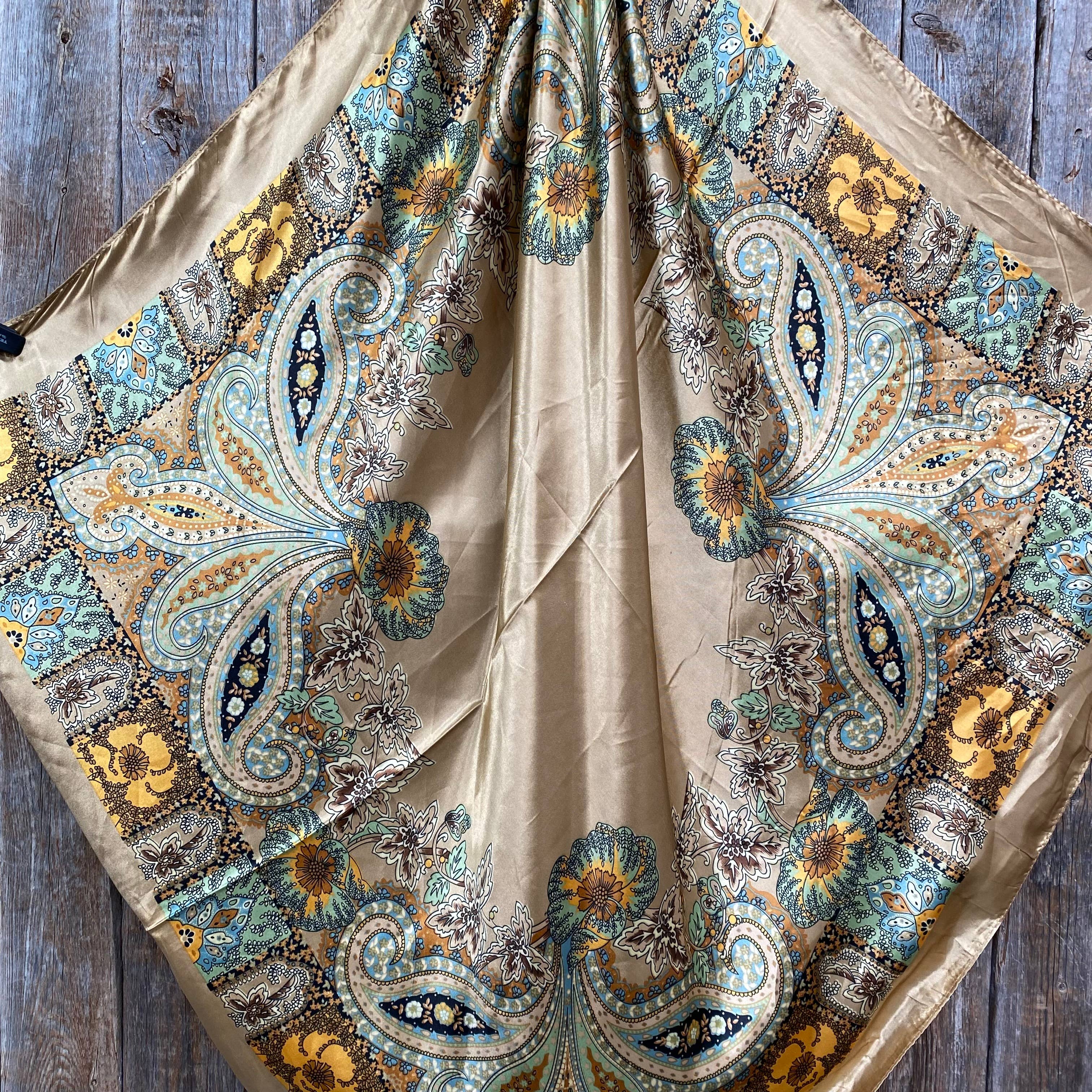 Decorative scarf with intricate paisley and floral patterns on a wooden surface