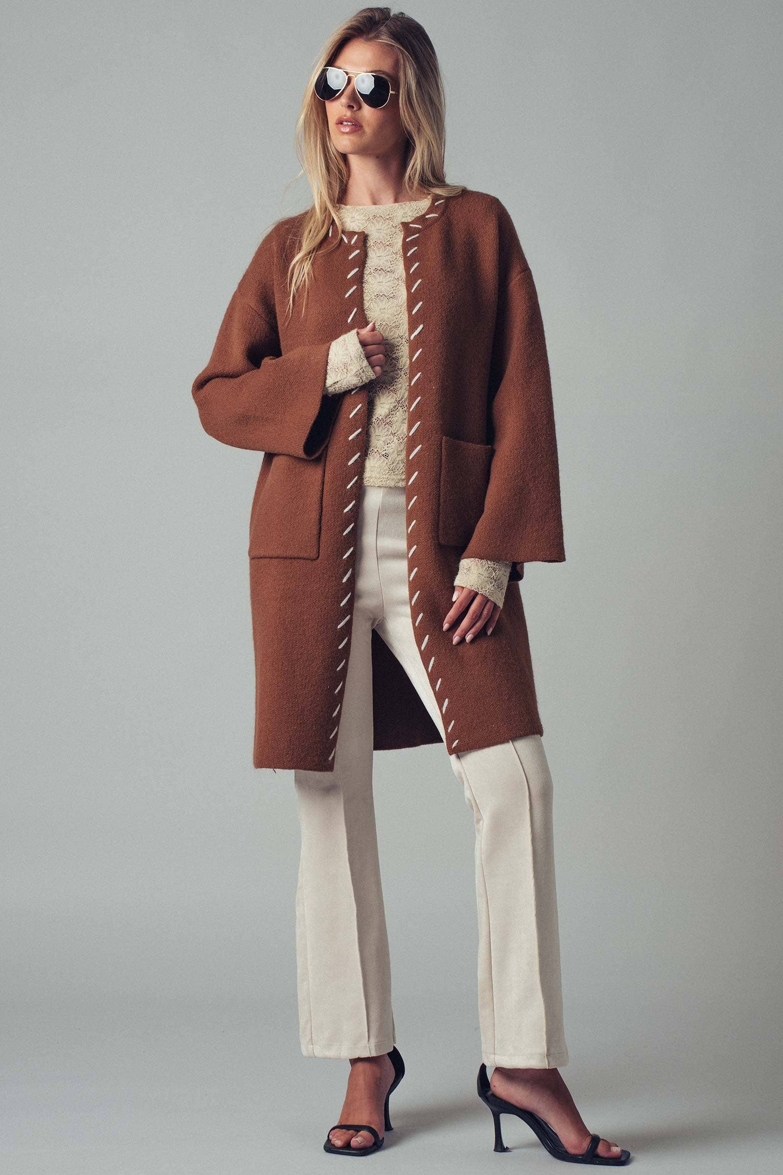 Woman wearing a brown open coat with white bold stitching trim