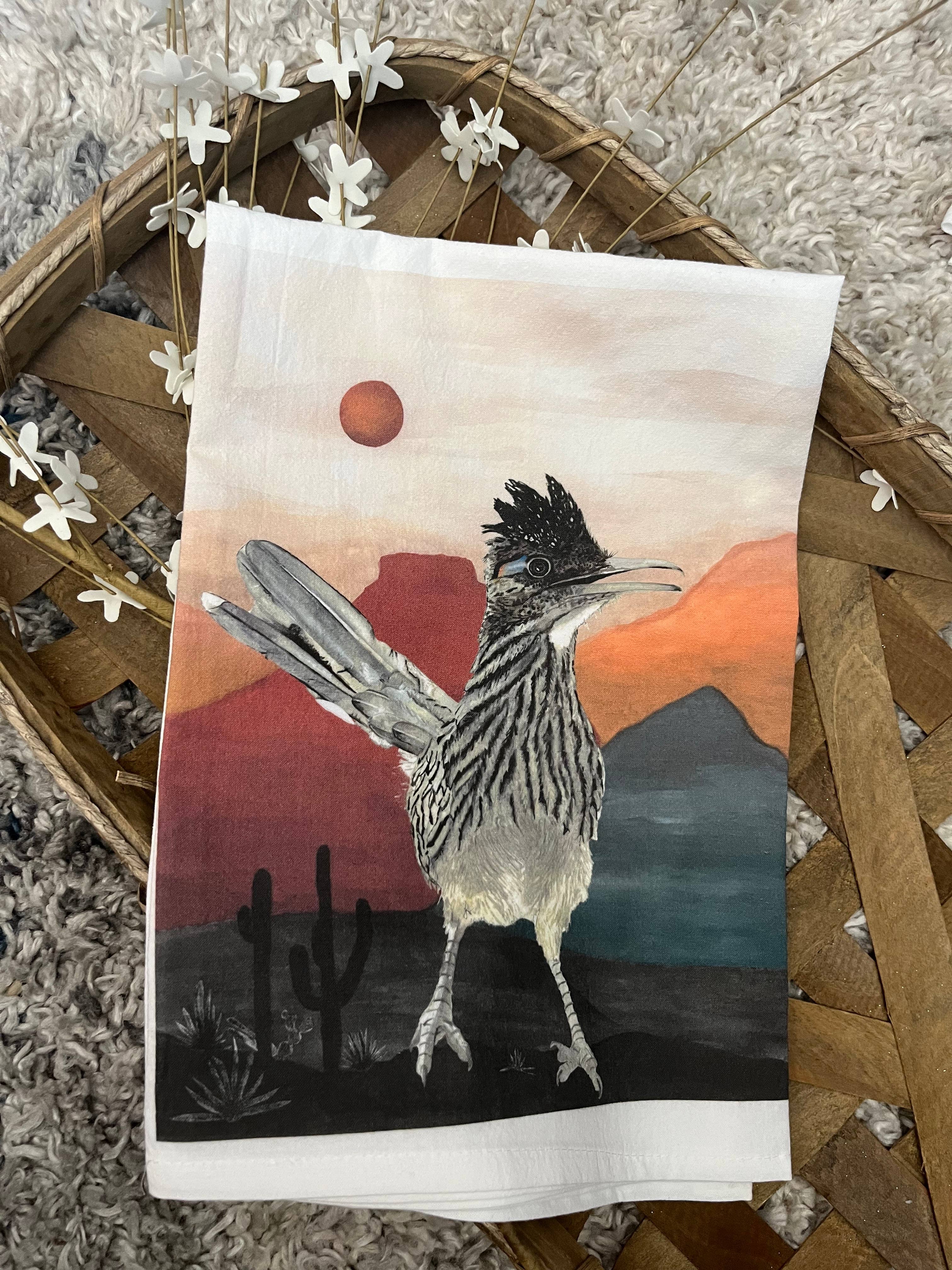 Tea towel with a desert scene and roadrunner design on a woven basket.
