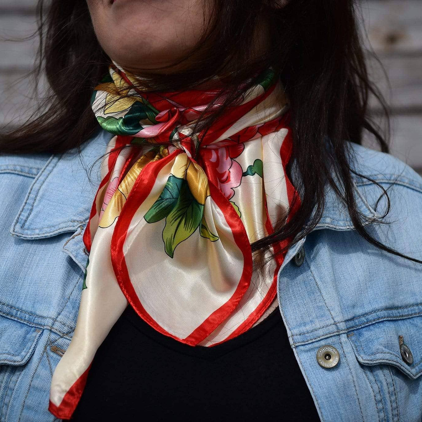 Person wearing a colorful scarf with floral patterns over a denim jacket.