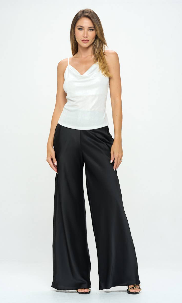 Woman wearing a white sleeveless top and black wide-leg pants on a white background
