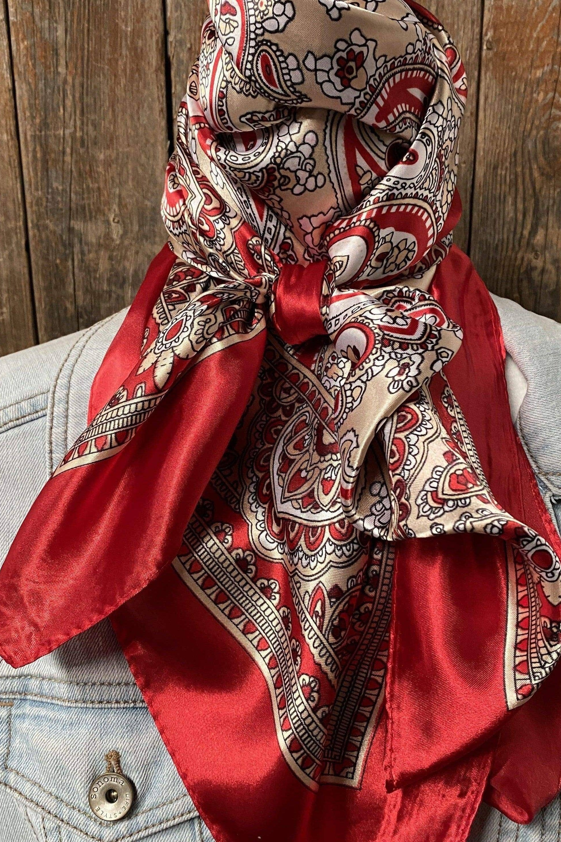 Red and beige patterned scarf draped over a light blue denim jacket against a wooden background