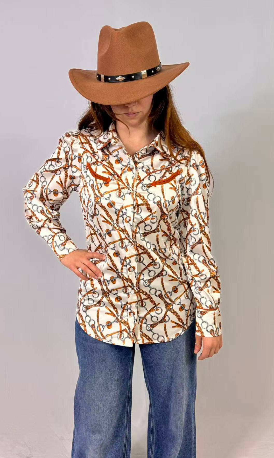 Person wearing a patterned shirt and brown hat against a plain background