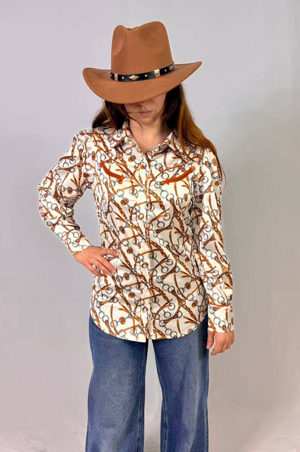 Person wearing a patterned shirt and brown hat against a plain background