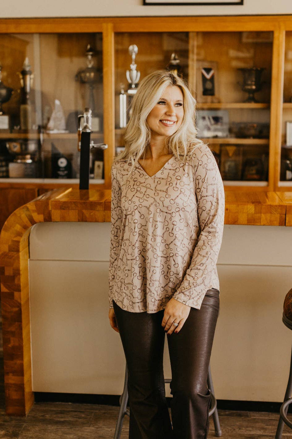 Front view of V-neck stretch top with roll-tab sleeves in a relaxed fit tan with brown horse bit pattern all over top