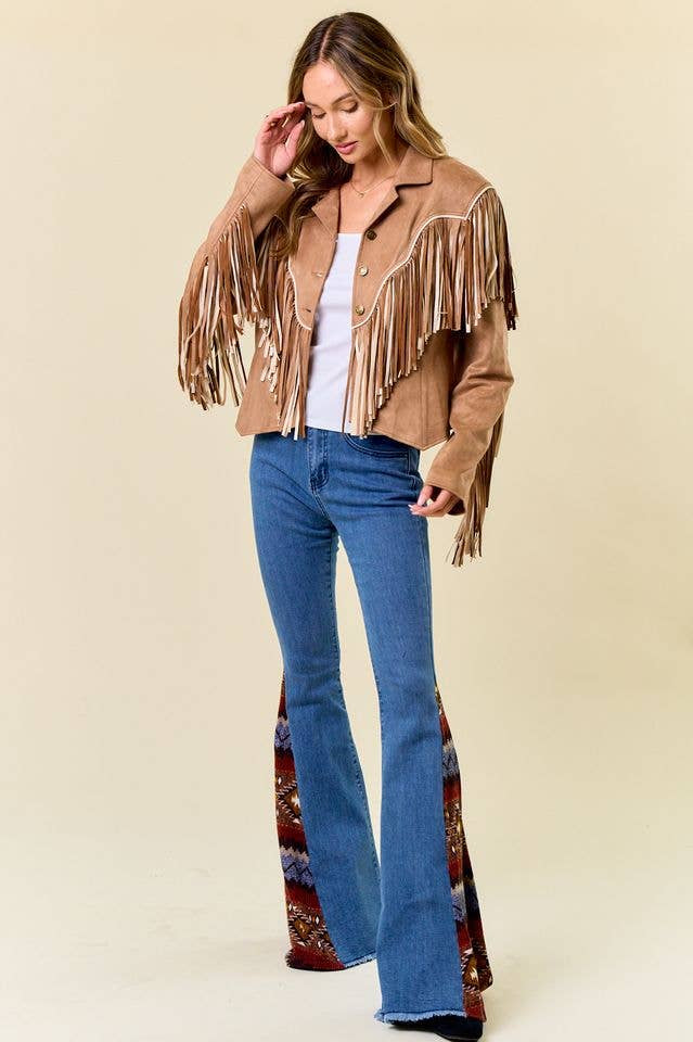 Woman wearing a brown fringe jacket and blue jeans against a beige background