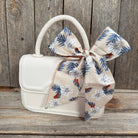 White handbag with a floral scarf ribbon on a wooden surface