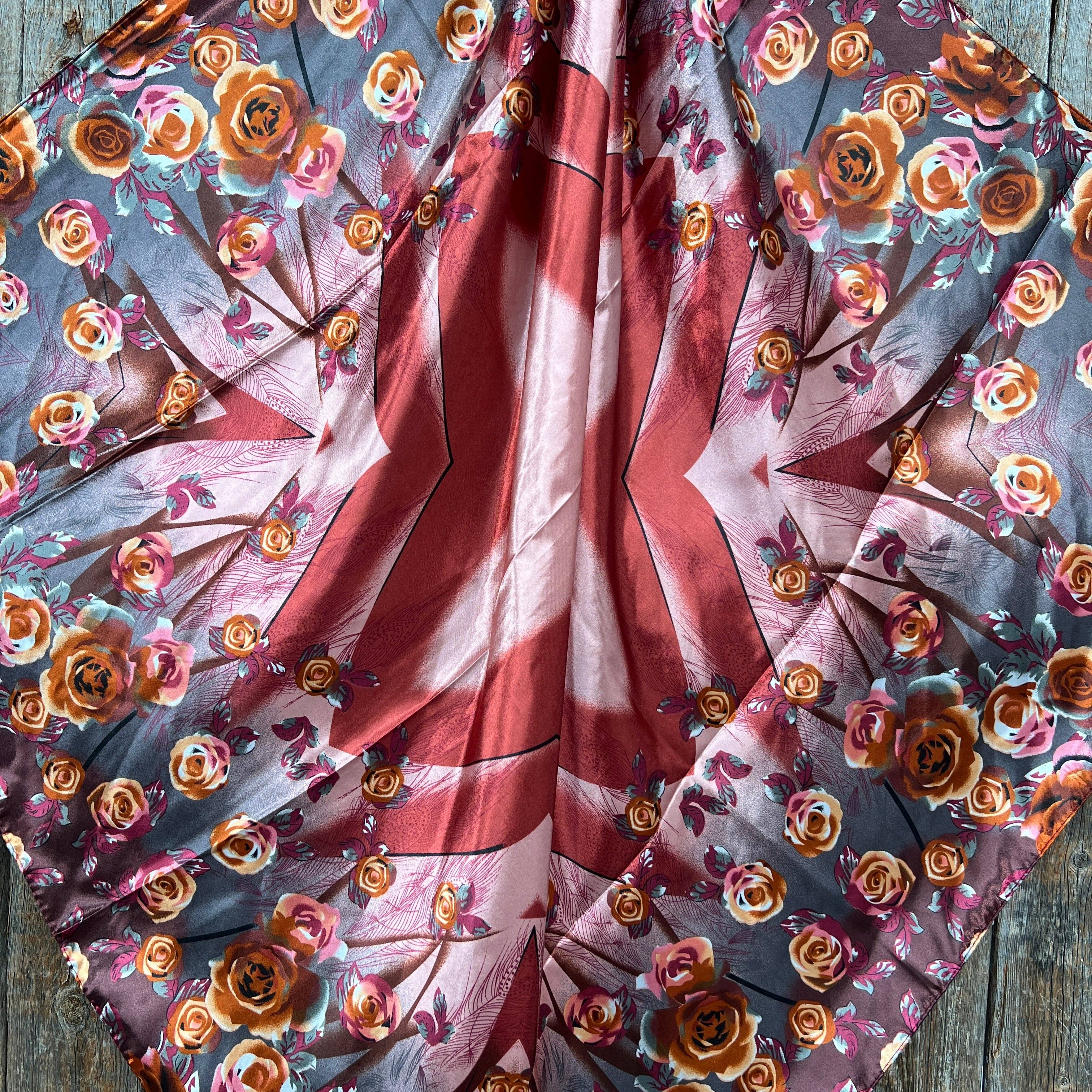 Floral fabric with a red,rust,pink and  white floral pattern on a wooden surface
