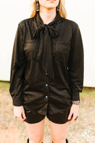 Person wearing a black long-sleeve shirt with a tie collar outdoors.