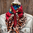 Colorful scarf with animal print draped over a denim jacket against a wooden background