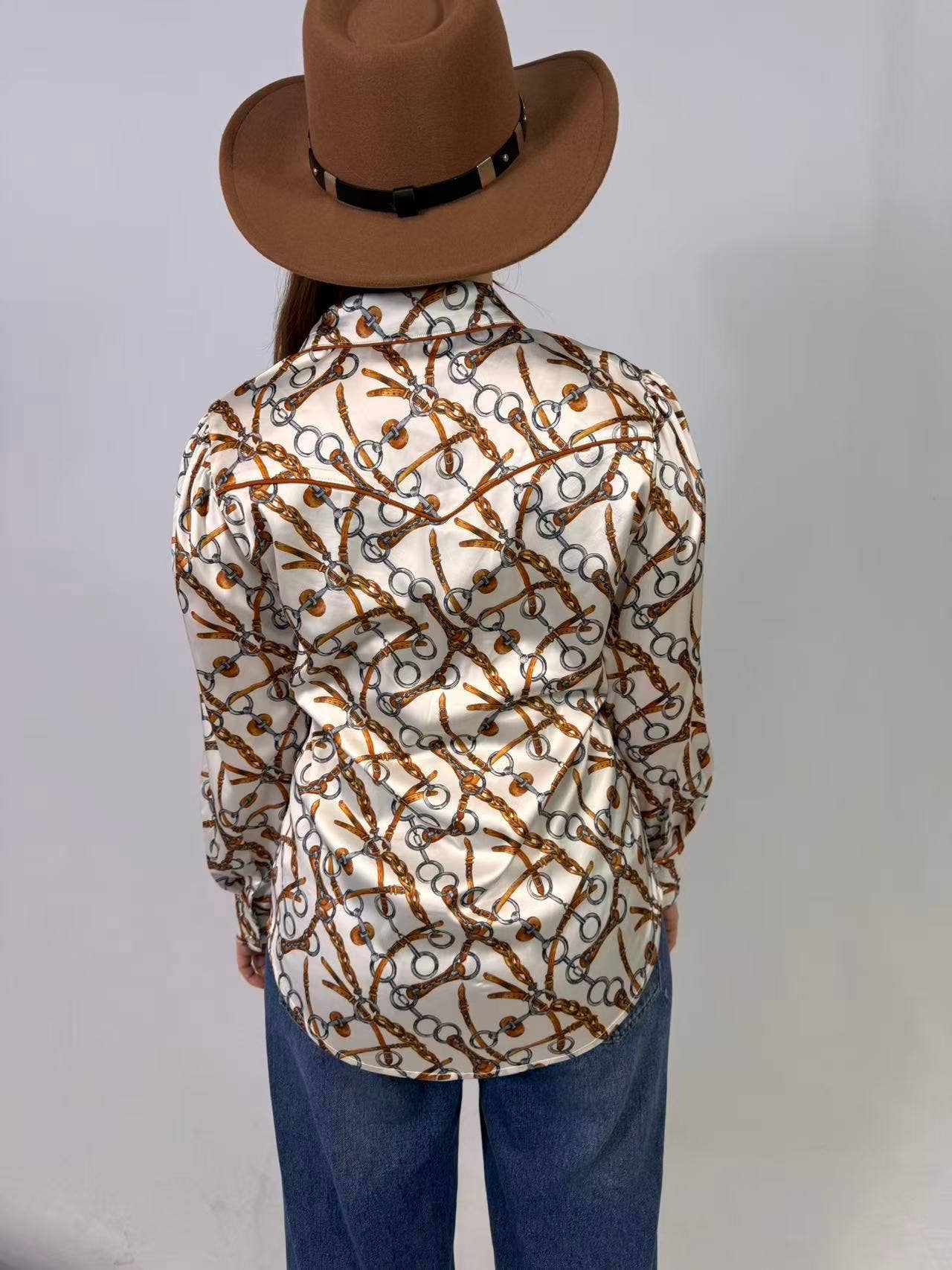 Person wearing a patterned shirt and brown hat on a plain background