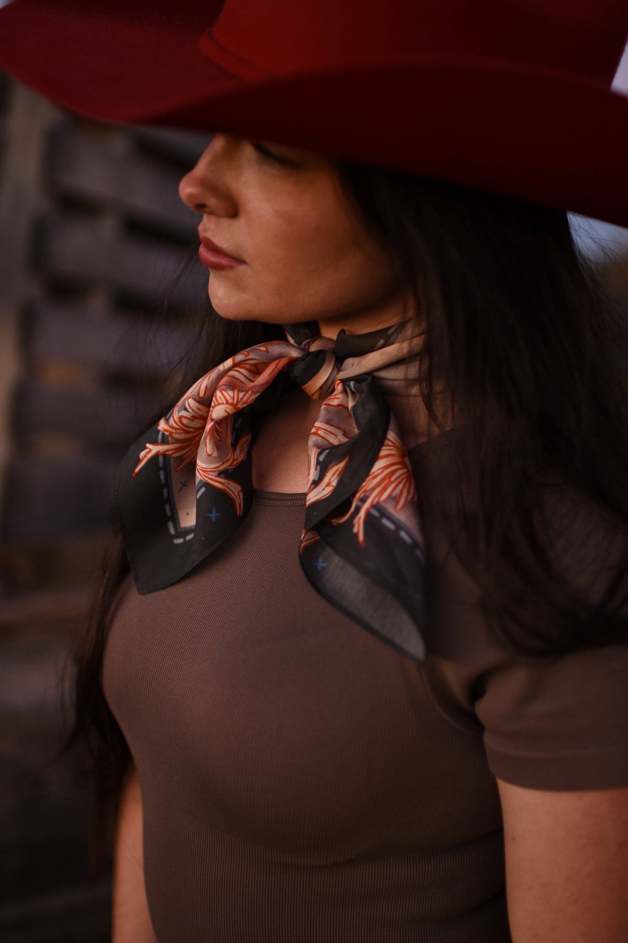 Woman wearing a red hat and brown top with a patterned scarf around her neck.