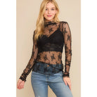 Woman wearing a sheer black top with lace details on a plain background
