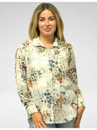 Woman wearing a patterned shirt with various designs on a plain background