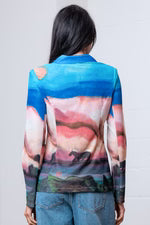 Person wearing a colorful long-sleeve blazer with abstract design on a plain background