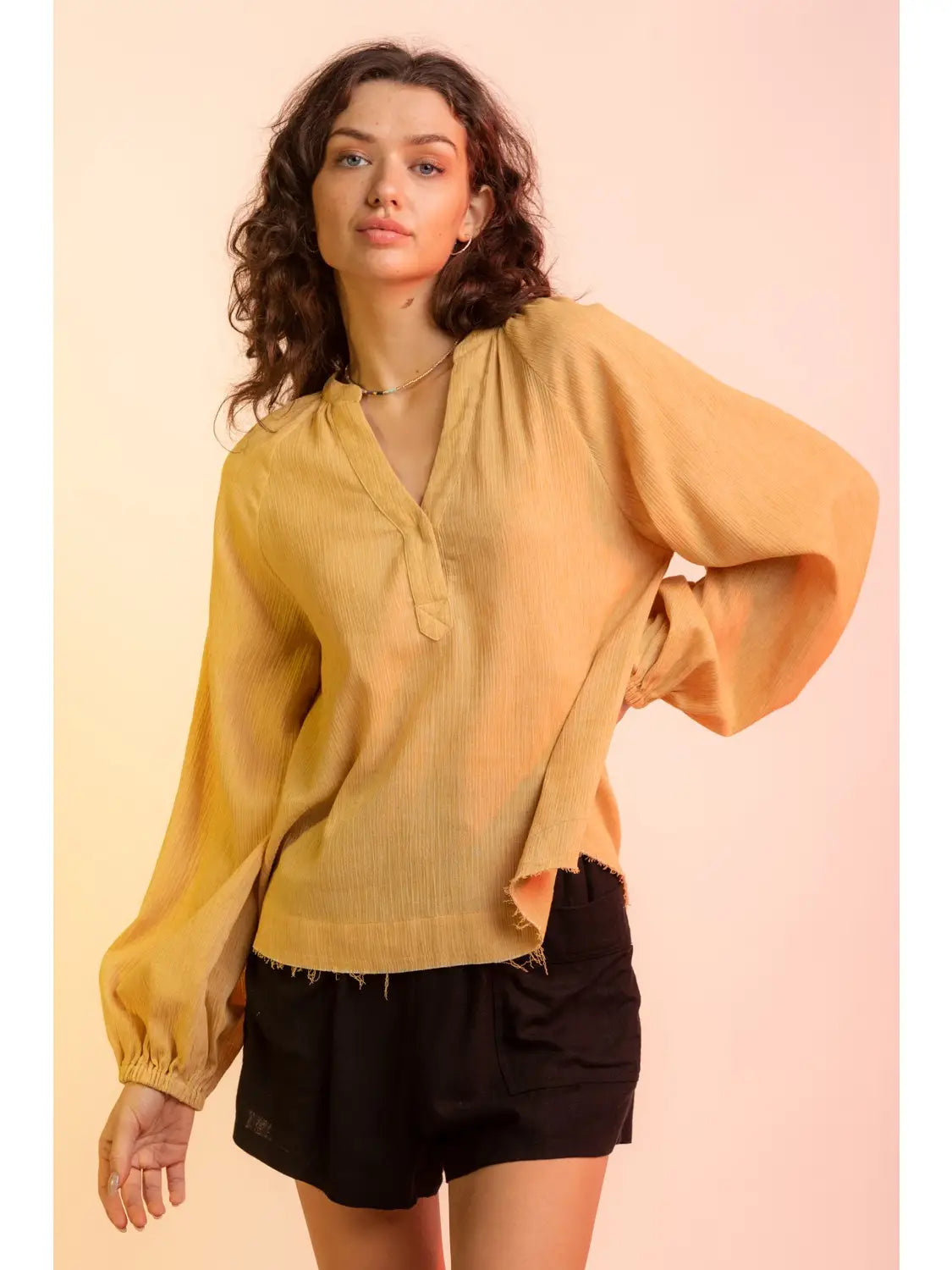 Front view, relaxed pose: Yellow V-neck gauze blouse with raw edge hem and billowy sleeves, model facing camera.