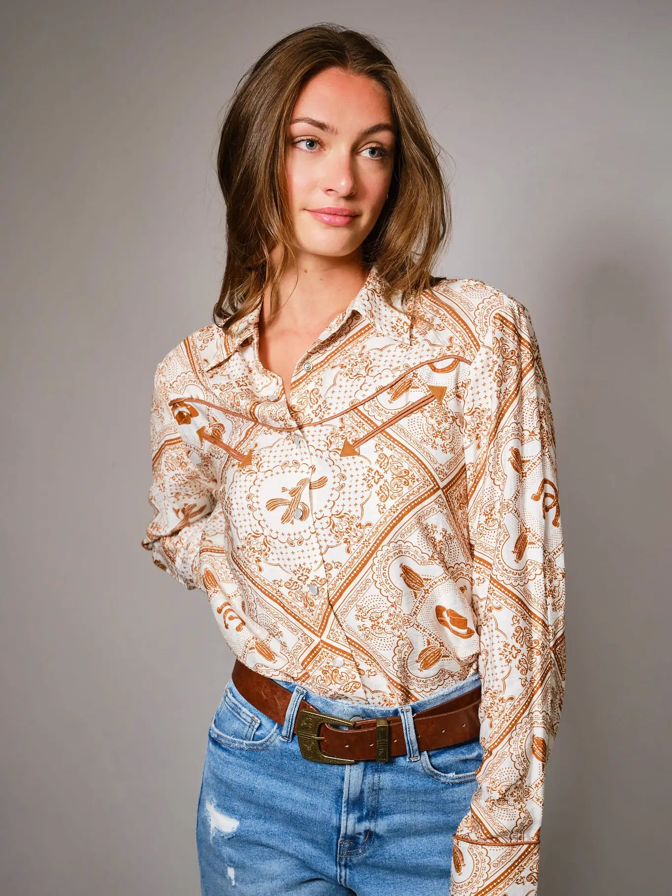 Woman wearing a western patterned blouse western color details snap shirt and jeans 
